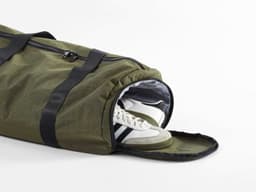 An olive green gym bag with a shoe pocket, featuring black straps and a zip opening.