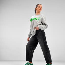 A grey unisex crew neck sweatshirt made from organic cotton, worn with black jeans and green sneakers, featuring a logo.