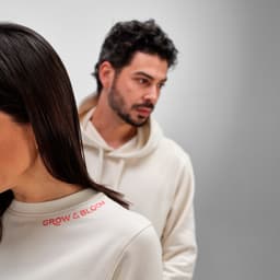 A cream-coloured women's crew neck sweatshirt made from organic cotton and rPET, featuring a logo on the front.