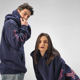 A navy hooded sweatshirt made from organic cotton, featuring a logo and a butterfly design, worn by two models.
