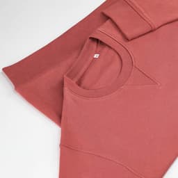 A crew neck sweatshirt in a rose pink hue, made from 100% organic cotton, featuring a soft terry texture and a logo.