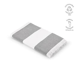 A grey and white striped towel with fringe edges, made of 100% sustainable materials, featuring a logo.