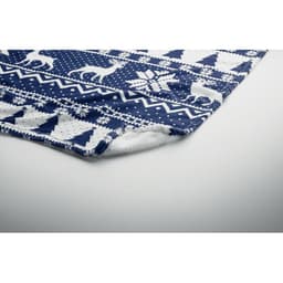 A soft fleece blanket with a navy blue and white Christmas pattern featuring trees and reindeer.
