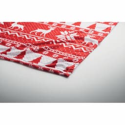 A red knitted blanket featuring festive white patterns, including reindeer and snowflakes, with a folded edge.