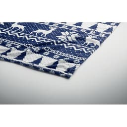A patterned blue blanket featuring white designs of reindeer, snowflakes, and geometric shapes, with a folded edge.