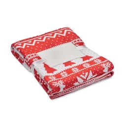 A folded red and white fleece blanket features holiday patterns, secured with a white ribbon.