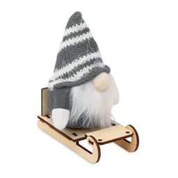 A grey gnome with a striped hat sits on a wooden sleigh. The gnome has a white beard and features a simple design.