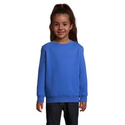 A blue sweatshirt for kids displayed on a young girl with brown hair, featuring a simple design and ribbed cuffs.