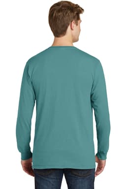 A man wears a teal pigment-dyed long sleeve tee, showcasing the back design. The shirt has a simple logo.