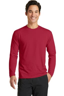 A man wearing a red long sleeve performance blend tee, paired with black pants and smiling. The shirt has a logo.