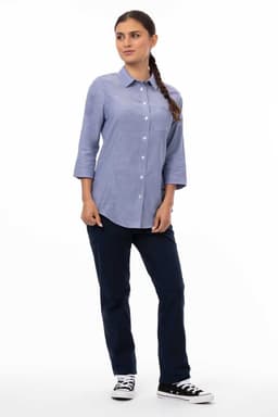 A blue women's classic shirt with three-quarter sleeves, paired with dark jeans and black sneakers, features a logo.