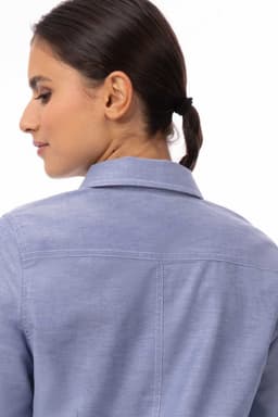 A classic women's shirt in light blue, featuring a collared neck and a back seam detail. It includes branding.