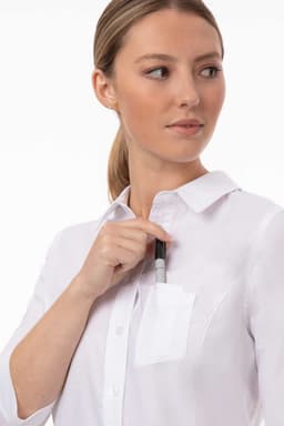 A woman wearing a white classic shirt with a pocket, holding a pen near the pocket. The shirt features a collar and button-up design.