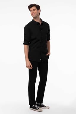 A men's black shirt with rolled sleeves, paired with black trousers and sneakers. The model stands casually.