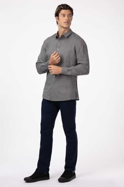 A men's black shirt with a button-down collar, featuring a logo on the sleeve, styled with dark trousers.