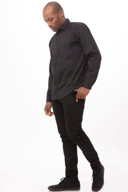 A black zip front shirt is displayed on a model, paired with black trousers and shoes. The shirt features a collar and long sleeves.