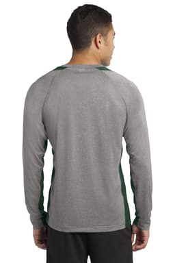 A man stands with his back to the camera, wearing a long sleeve grey and green colourblock tee.