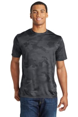 A man models a black camo-patterned Sport-Tek CamoHex Tee, featuring a logo on the shirt.