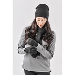 A woman wearing a black knit beanie, matching scarf, and gloves, styled with a grey long-sleeve top.