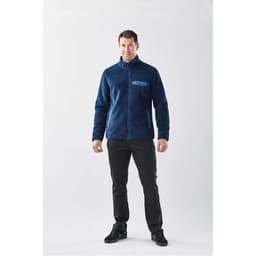 A man wearing a navy blue men's Bergen Sherpa fleece jacket, paired with black pants and dark shoes.