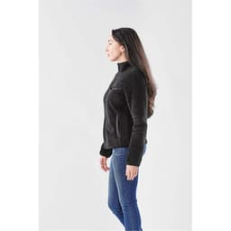 A woman in a black Sherpa fleece jacket, featuring a zip and side pockets, set against a plain background.