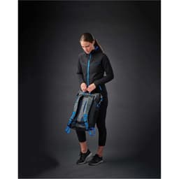 A woman wearing a black women's Logan Performance Hoody with blue accents, holding a bag against a dark background.
