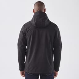 A black softshell jacket with a hood, featuring a logo, shown from the back on a model.