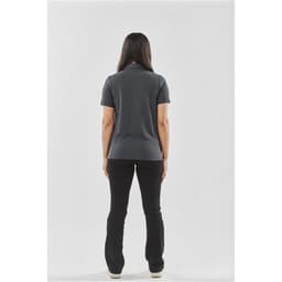 A woman stands with her back to the camera, wearing a dark grey women's polo shirt paired with black pants.