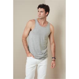 A grey men's tank top on a model, featuring a logo and styled with white trousers.