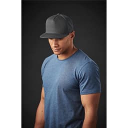 A grey crew neck tee worn by a model, paired with a black cap, against a dark background.