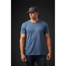 A men's crew neck T-shirt in blue, paired with a black cap, displayed on a model against a dark background.