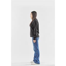 A side view of a woman wearing a black fleece crew neck jumper paired with blue jeans.