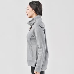 A grey women's cowl neck pullover jumper, featuring a high collar and side pockets, displayed on a model from the side.