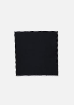 A square swatch of fabric in black with a zigzag edge, featuring a logo in the corner.