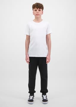 A pair of black track pants for youth, paired with a plain white t-shirt and black shoes.