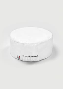 A white chef cap with a round shape and an elastic band at the back. It features a small logo tag.