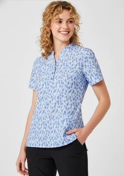 A blue tunic with a stardust print, featuring short sleeves and a collar, displayed on a smiling model.