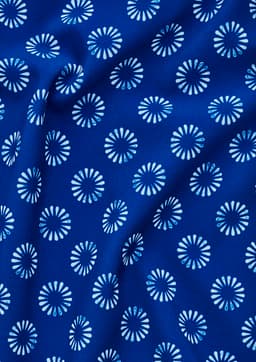 A blue tunic fabric featuring a white daisy print pattern. The material appears smooth and has a draping quality.
