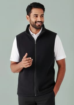 A man wearing a black plain micro fleece vest with a zip and a white shirt underneath. The vest has a collar and a logo.