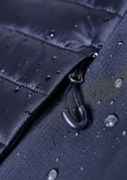 A close-up of a black soft shell jacket featuring a zippered opening and water droplets on the fabric.