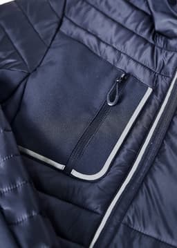 A navy unisex patrol jacket featuring a zippered chest pocket and quilted design. Logos are visible on the jacket.