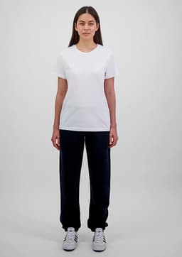 A woman stands wearing a white t-shirt and navy blue track pants, showcasing a simple, casual outfit.