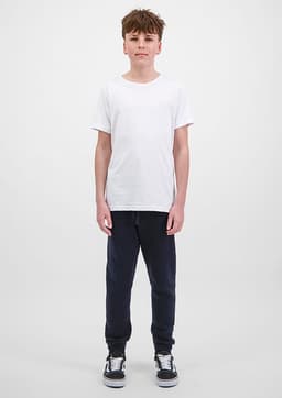 A young person is wearing navy track pants and a plain white t-shirt, standing against a light background.