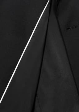 A close-up of the inside lining of a black jacket featuring a contrasting white trim and a sleek design.