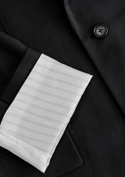 A black jacket featuring a white pinstriped sleeve cuff and a button detail, with a visible brand logo.
