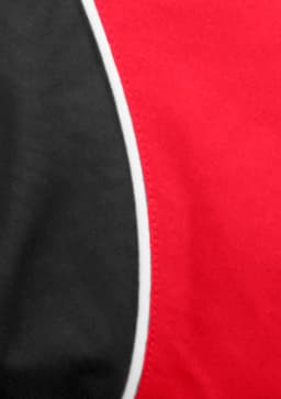 A close-up of a red and black short sleeve shirt with contrasting piping details and a logo.