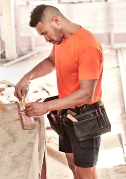 A men's high visibility t-shirt in bright orange, worn by a tradesman measuring wood, with a tool belt.