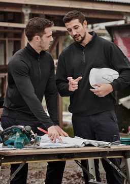 A black unisex Merino wool mid-layer pullover is worn by two men discussing plans at a construction site.