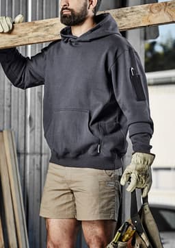 A dark grey unisex multi-pocket hoodie, worn by a person holding a wooden beam, featuring an attached logo.