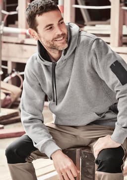A grey unisex multi-pocket hoodie featuring a logo, worn by a person sitting on a wooden surface.